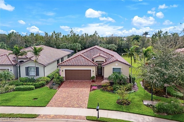 mediterranean / spanish-style house featuring an attached garage, a tiled roof, decorative driveway, stucco siding, and a front lawn