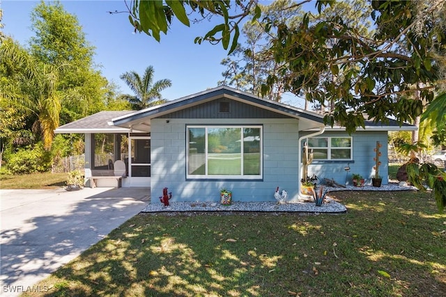 view of front of home with concrete driveway, a front lawn, and a sunroom