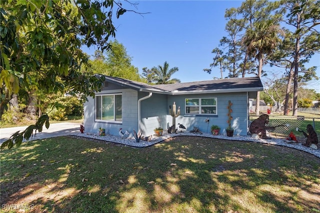 view of front of home featuring concrete block siding, a front lawn, and fence