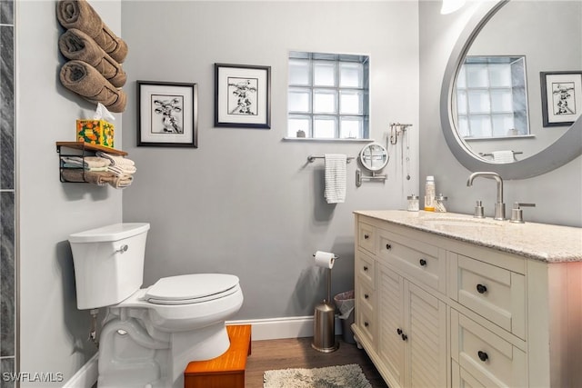 bathroom featuring baseboards, toilet, wood finished floors, and vanity