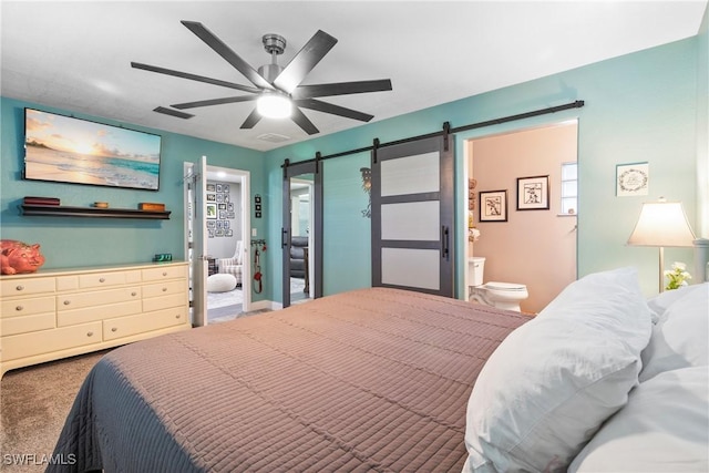 bedroom with connected bathroom, a ceiling fan, a barn door, and carpet floors