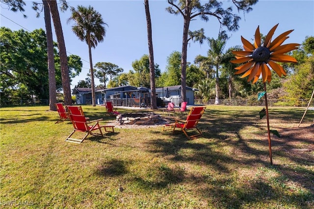 view of property's community featuring a yard, a fire pit, and fence