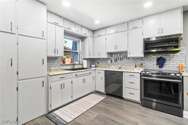 kitchen with a sink, tasteful backsplash, white cabinetry, appliances with stainless steel finishes, and light wood finished floors