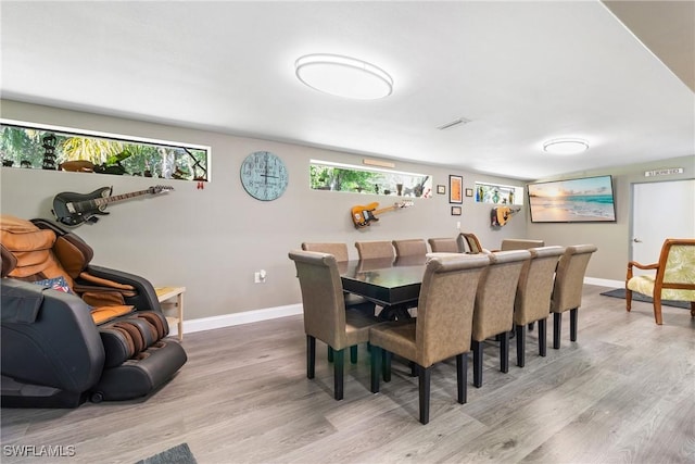 dining room featuring visible vents, baseboards, and light wood finished floors