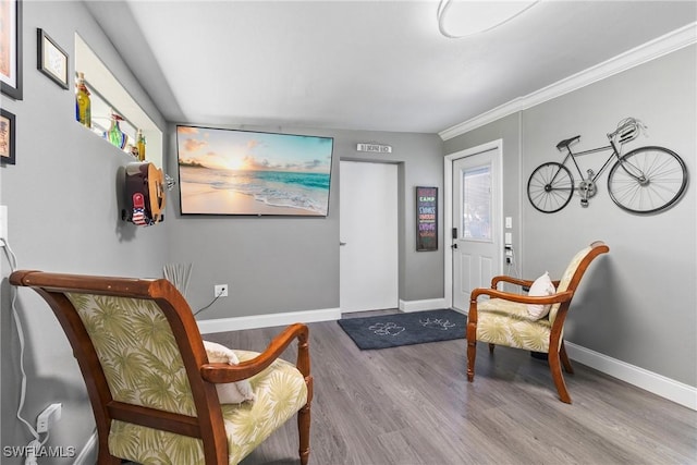 living area featuring a healthy amount of sunlight, ornamental molding, baseboards, and wood finished floors