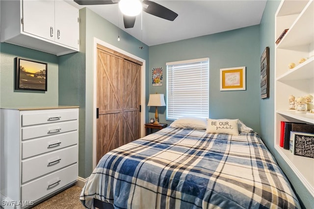 bedroom with a barn door, a closet, dark colored carpet, baseboards, and ceiling fan