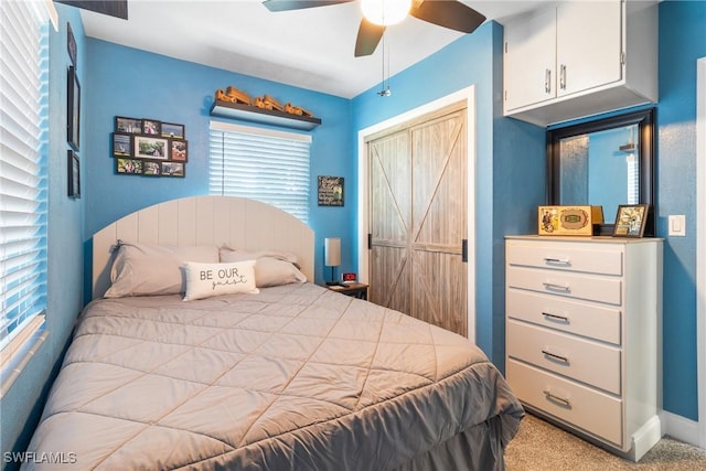 bedroom featuring carpet, baseboards, ceiling fan, a closet, and a barn door