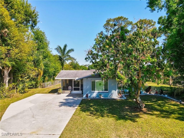 view of front of home with driveway, a front lawn, and a sunroom