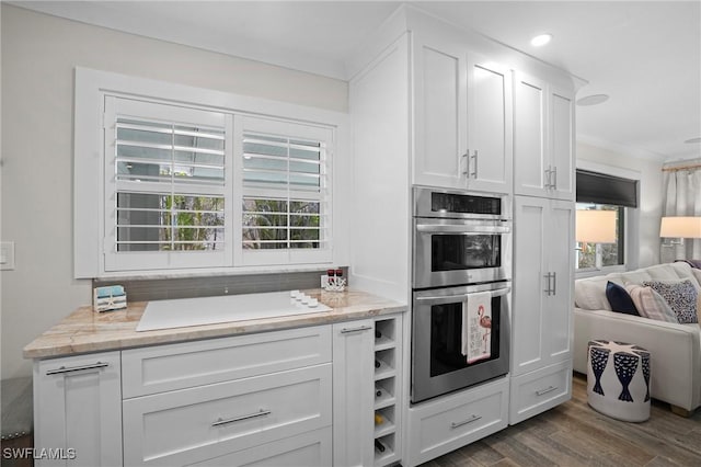 kitchen featuring white stovetop, stainless steel double oven, white cabinets, and a healthy amount of sunlight