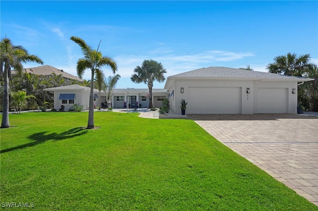 ranch-style house with an attached garage, stucco siding, decorative driveway, and a front yard