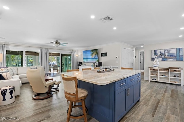 kitchen featuring a center island, open floor plan, blue cabinetry, and wood finished floors