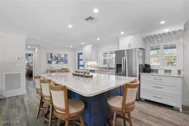 kitchen featuring white cabinets, visible vents, crown molding, and wood finished floors