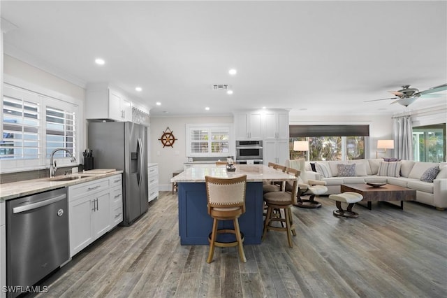 kitchen with appliances with stainless steel finishes, open floor plan, crown molding, and a sink