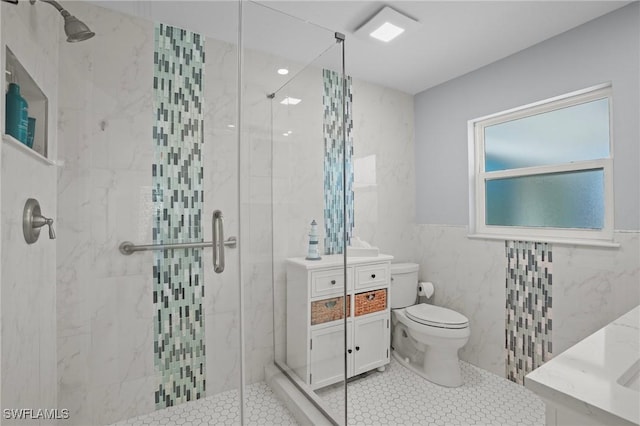 bathroom featuring tile walls, toilet, a stall shower, vanity, and tile patterned flooring