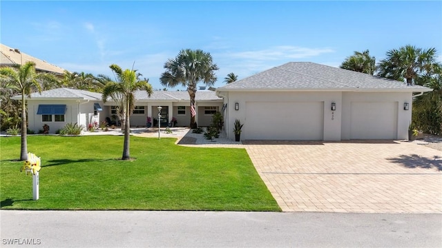 single story home with decorative driveway, an attached garage, stucco siding, and a front yard