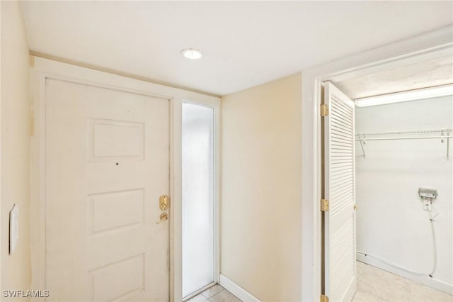 foyer entrance featuring light tile patterned floors and baseboards