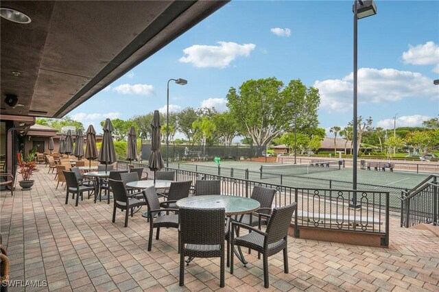 view of patio with a tennis court and outdoor dining space