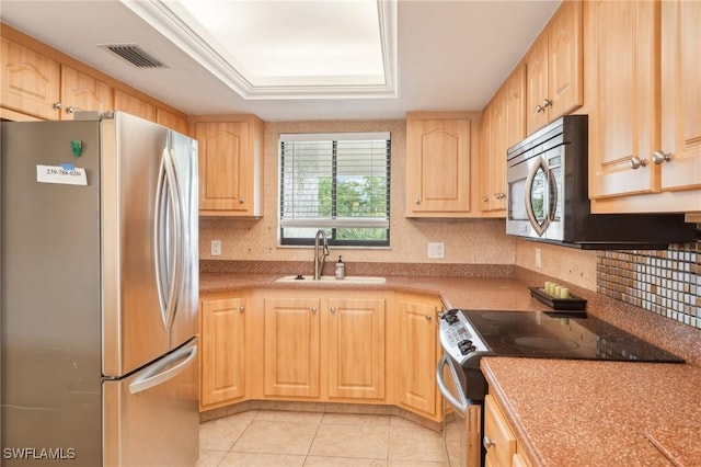 kitchen with stainless steel appliances, light brown cabinets, and a sink