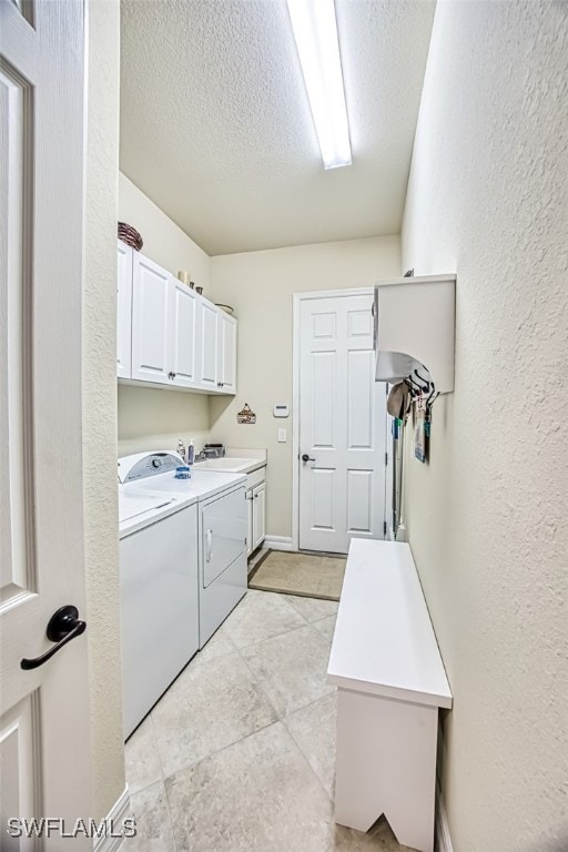 laundry area with washing machine and clothes dryer, cabinet space, a textured ceiling, and a textured wall