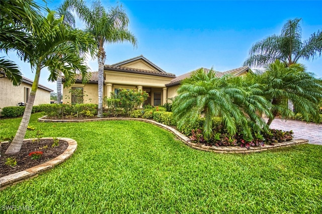 view of front facade featuring stucco siding, a front yard, and a tiled roof