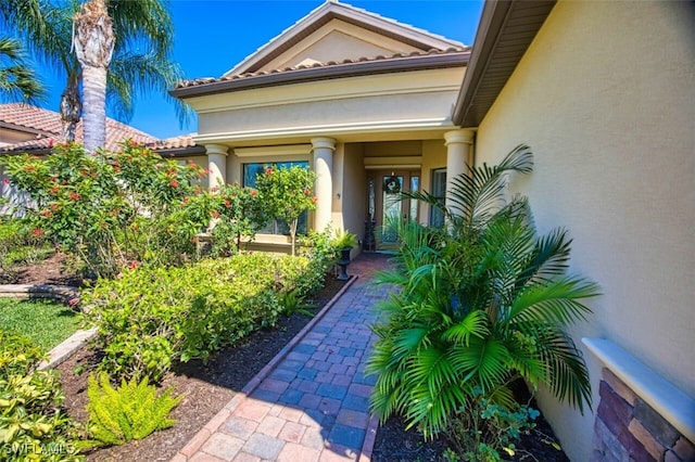 entrance to property with a tiled roof and stucco siding