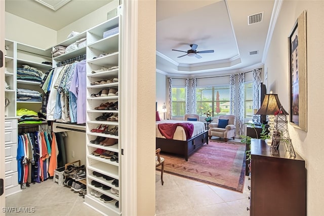 walk in closet with tile patterned flooring, a tray ceiling, visible vents, and ceiling fan