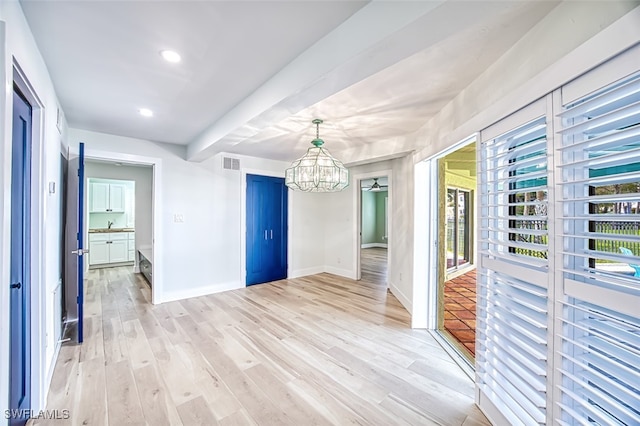 unfurnished dining area featuring light wood-type flooring, an inviting chandelier, baseboards, and visible vents