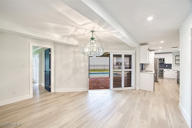 unfurnished dining area featuring a notable chandelier, baseboards, a wealth of natural light, and light wood-style floors