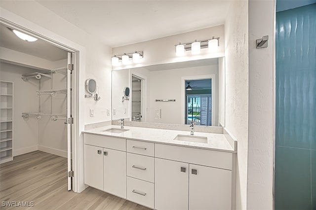 full bath featuring double vanity, wood finished floors, a spacious closet, and a sink