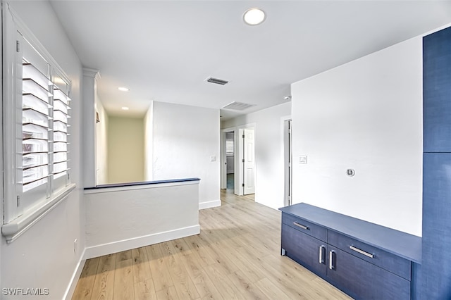 spare room featuring light wood-type flooring, visible vents, and baseboards