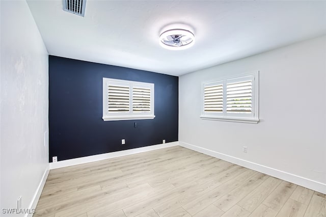 spare room with visible vents, baseboards, and wood finished floors