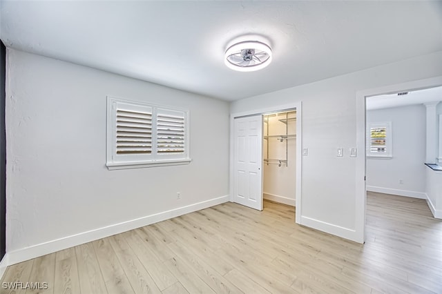 unfurnished bedroom with light wood-type flooring, a closet, and baseboards