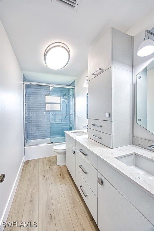 bathroom with toilet, double vanity, a sink, and wood finished floors