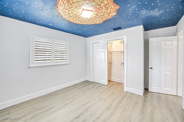 unfurnished bedroom with visible vents, baseboards, and wood finished floors