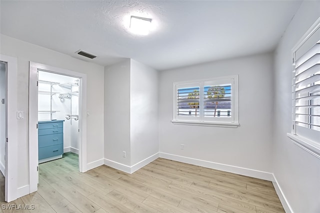 spare room with light wood-style floors, baseboards, and visible vents