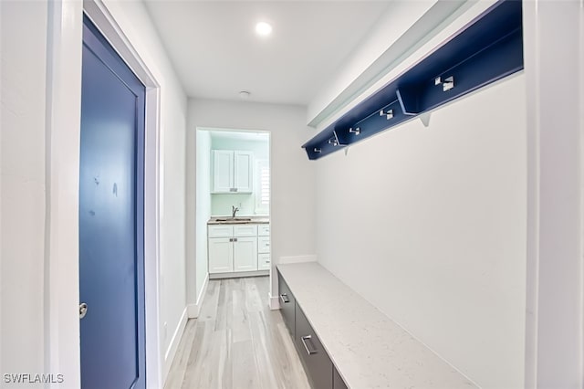 mudroom featuring light wood finished floors, baseboards, and a sink