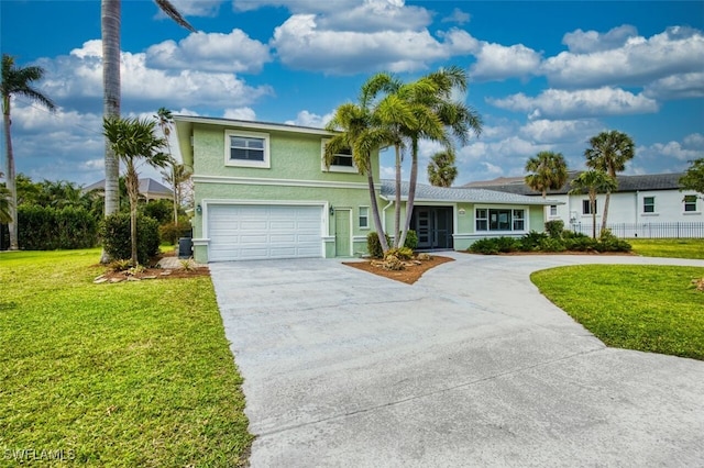 traditional-style home featuring driveway, stucco siding, fence, and a front yard