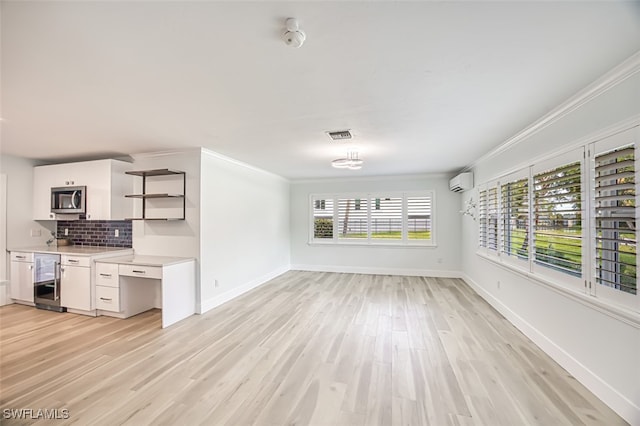 interior space featuring beverage cooler, white cabinets, stainless steel microwave, an AC wall unit, and open shelves