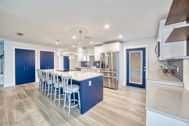 kitchen with appliances with stainless steel finishes, light wood-type flooring, a kitchen bar, and white cabinets