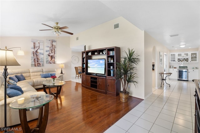 tiled living room featuring arched walkways, visible vents, ceiling fan, a bar, and beverage cooler