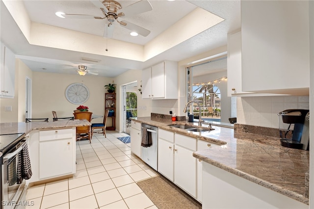 kitchen with stainless steel appliances, a tray ceiling, a sink, and white cabinetry