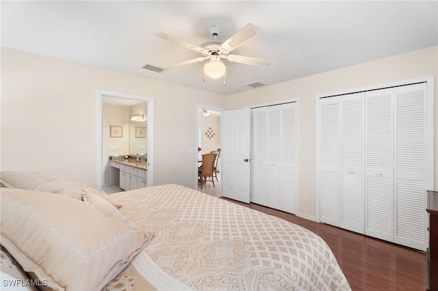 bedroom featuring visible vents, ensuite bath, ceiling fan, wood finished floors, and multiple closets