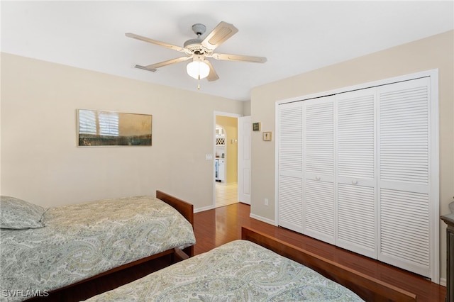 bedroom with a closet, visible vents, ceiling fan, wood finished floors, and baseboards