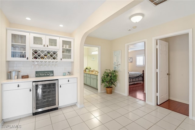 bar featuring wine cooler, a dry bar, light tile patterned floors, visible vents, and backsplash