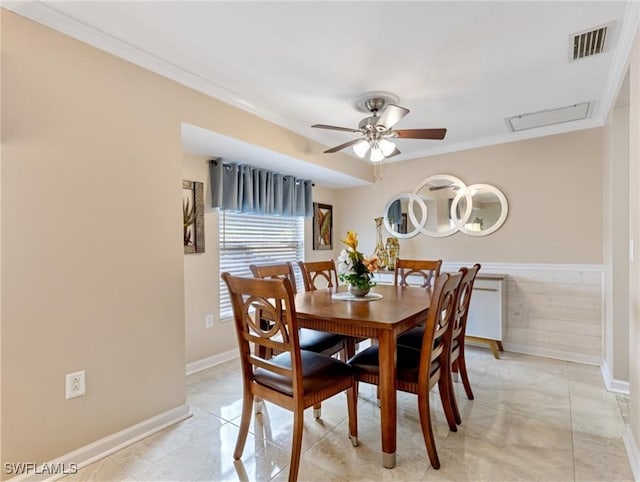 dining room featuring baseboards, visible vents, ceiling fan, ornamental molding, and wainscoting