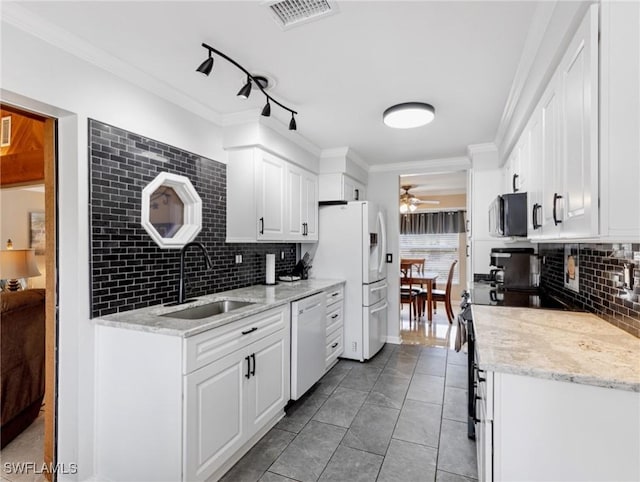 kitchen with white appliances, visible vents, ornamental molding, a sink, and white cabinets