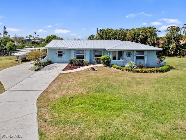 ranch-style home featuring a front yard, stucco siding, driveway, and metal roof