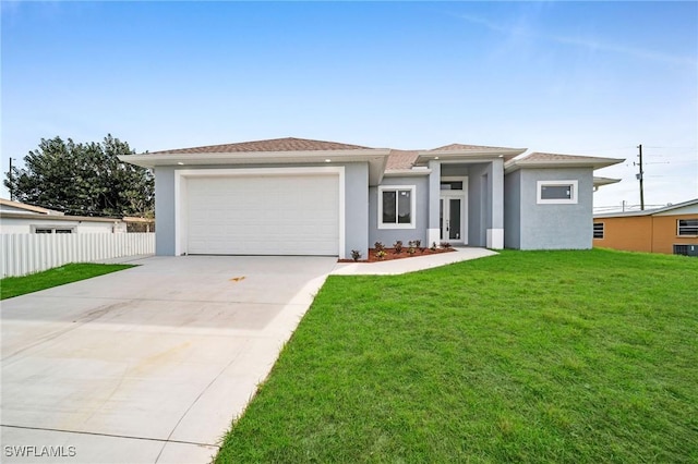 prairie-style home featuring stucco siding, concrete driveway, a front yard, fence, and a garage