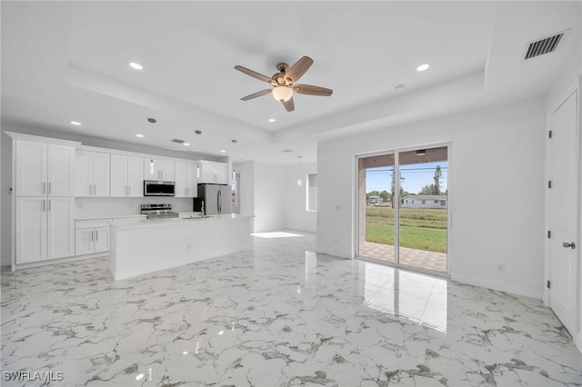 kitchen with a tray ceiling, recessed lighting, visible vents, appliances with stainless steel finishes, and white cabinetry