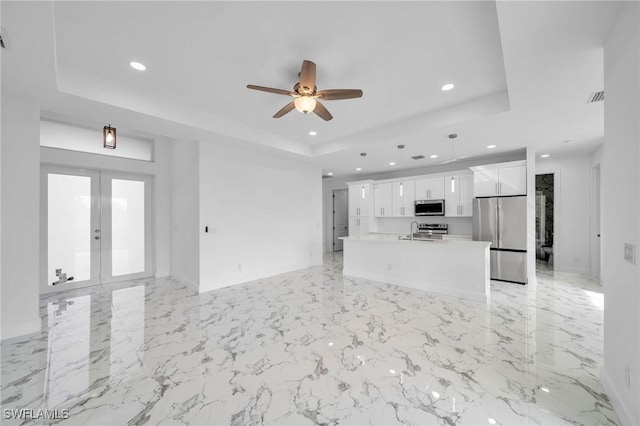 unfurnished living room featuring french doors, a tray ceiling, visible vents, and recessed lighting